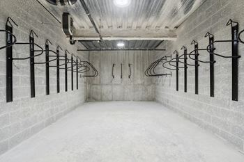 A long hallway with a white floor and walls, and black metal racks on the wall.